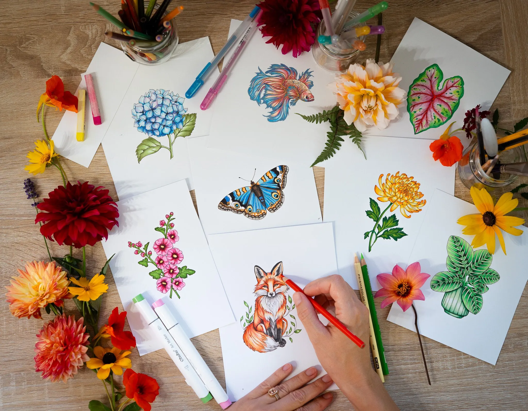 Rachel coloring a fox illustration among flowers and colored pages