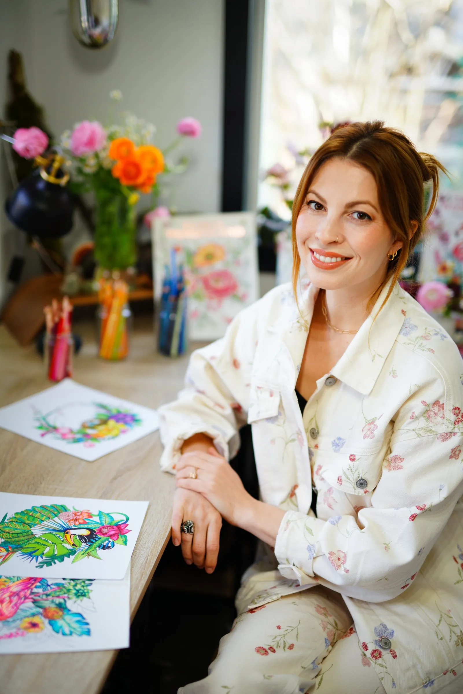 Rachel Reinert at her studio table with flowers and colored pages