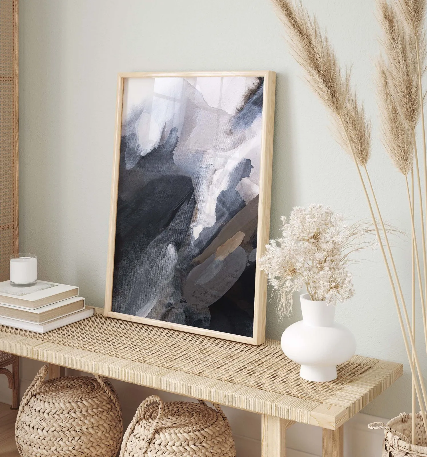 Grey and beige abstract painting on a rattan bench beside pampas grass